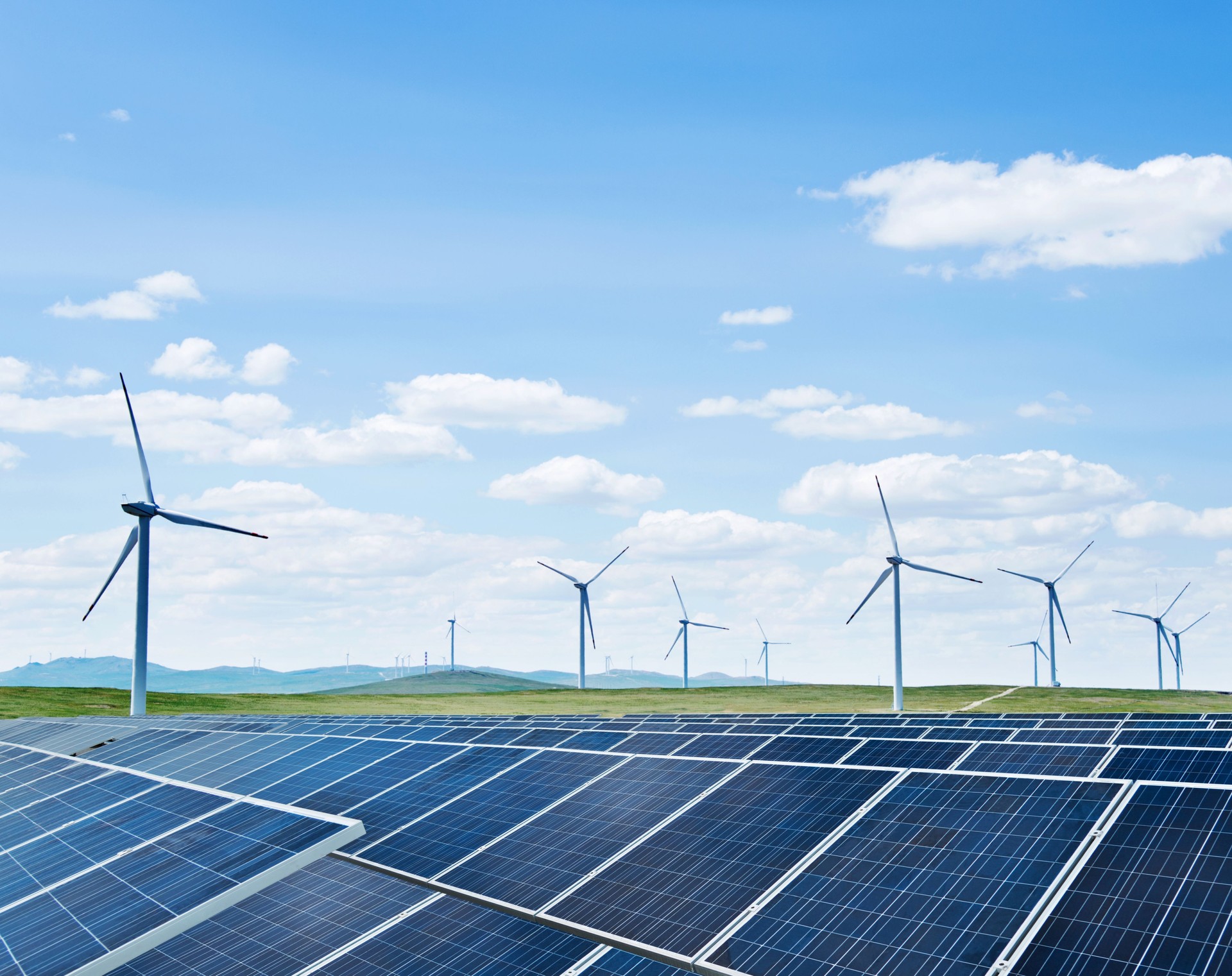 Wind power generation and solar panels against blue sky